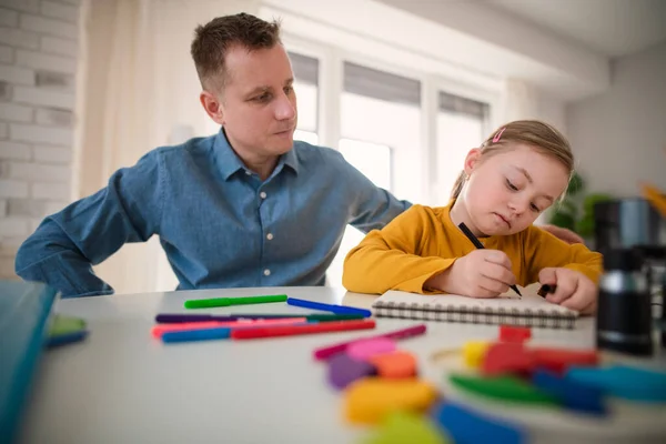 Vater mit kleiner Tochter mit Down-Syndrom lernt zu Hause. — Stockfoto