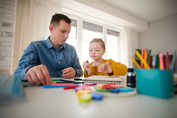 Vader met zijn dochtertje met het syndroom van Down thuis leren. — Stockfoto