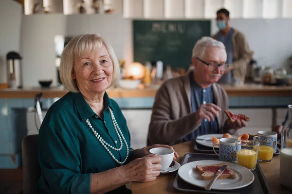 Leende äldre kvinna och man njuter av frukost på vårdhemmet. — Stockfoto