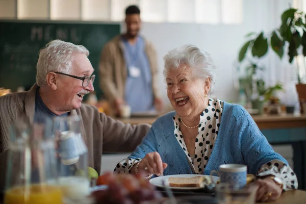 老人ホームで朝食を楽しむ笑顔の女性と男. — ストック写真