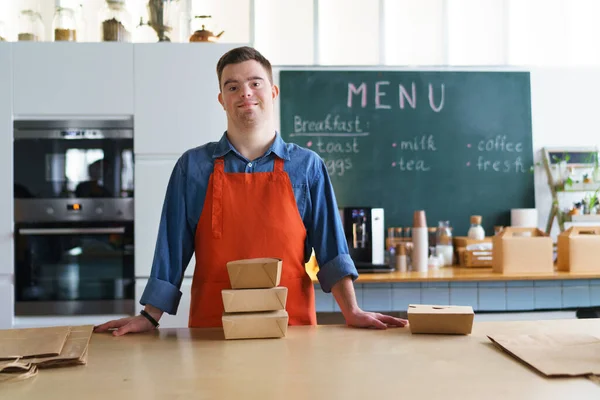 Jovem e alegre garçom da Síndrome de Down trabalhando no restaurante take away, conceito de inclusão social. — Fotografia de Stock