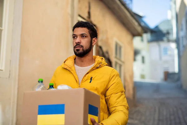 Caja de cyrrying voluntario con ayuda humanitaria para refugiados ucranianos en la calle — Foto de Stock