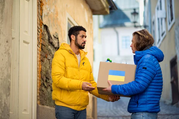 Voluntarios recogiendo cajas con ayuda humanitaria para refugiados ucranianos en la calle — Foto de Stock