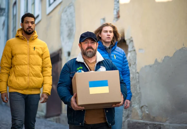 Une équipe de bénévoles collecte des boîtes avec de l'aide humanitaire pour les immigrants ukrainiens dans la rue — Photo