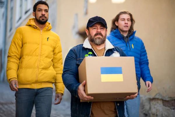Une équipe de bénévoles collecte des boîtes avec de l'aide humanitaire pour les immigrants ukrainiens dans la rue — Photo