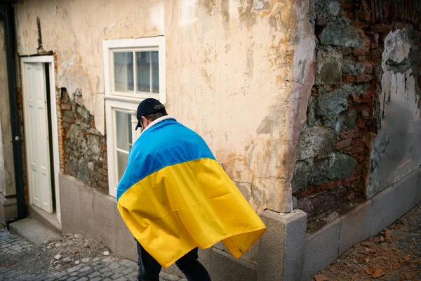 Протестант покритий синьо-жовтим прапором України, який протестує проти війни в Україні. — стокове фото