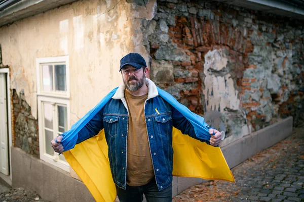 Protestor covered with blue and yellow Ukrainian flag protesting against war in Ukraine in street — Stock Photo, Image