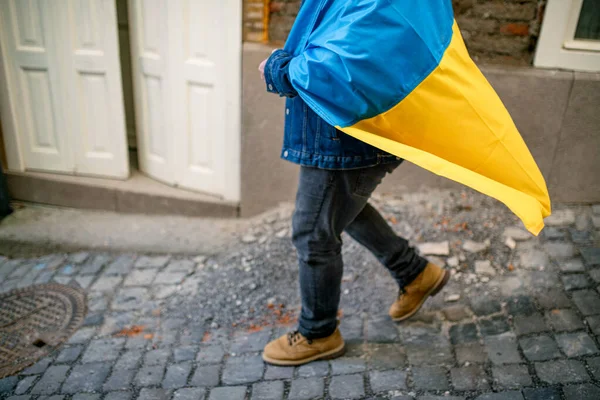 Нижняя часть протестующего, покрытая сине-желтым флагом Украины, протестует против войны на Украине на улице — стоковое фото