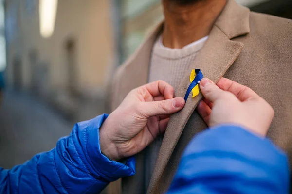Organizador de protesta distribuye cintas azules y amarillas ucranianas a personas que protestan contra la guerra en Ucrania —  Fotos de Stock