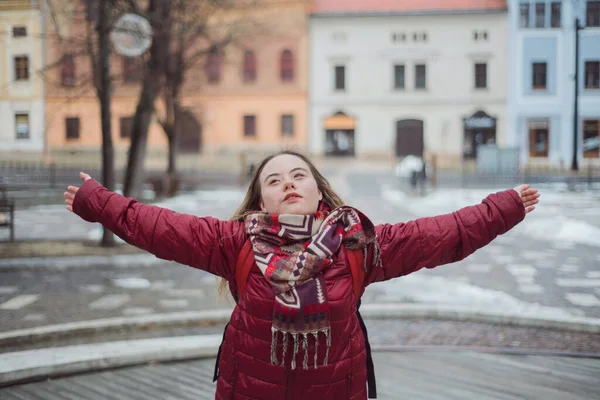 Glückliche junge Frau mit Down-Syndrom im Winter mit offenen Armen in der Stadt — Stockfoto