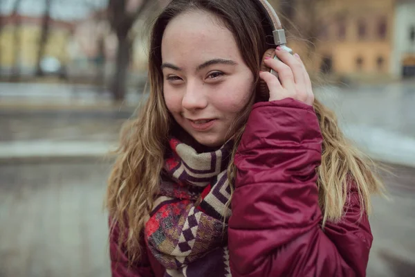 Счастливая молодая женщина с синдромом Дауна, слушающая музыку в городе зимой — стоковое фото