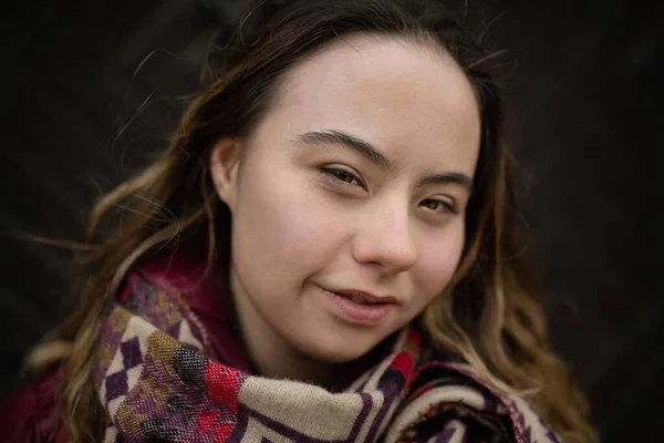 Nahaufnahme einer jungen Frau mit Down-Syndrom, die auf schwarzem Hintergrund in die Kamera blickt — Stockfoto