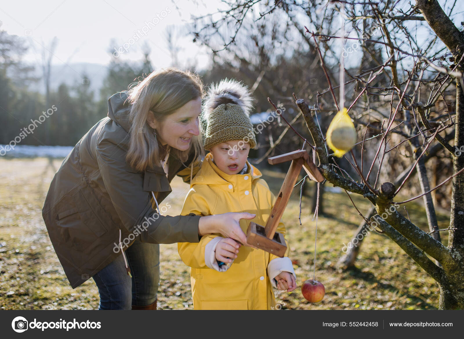 Boy with Down syndrome feeding birds in garden in winter with his