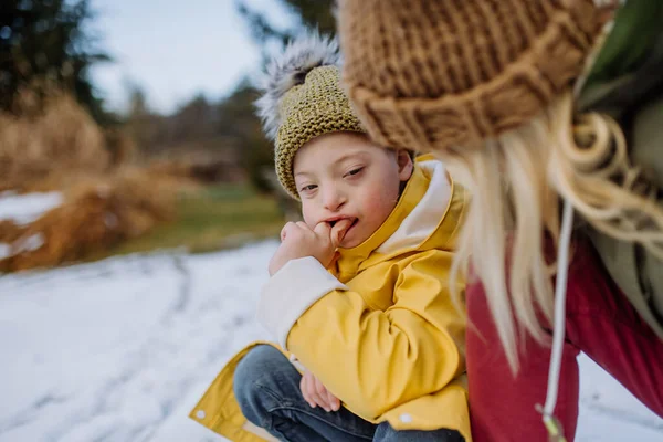 Annesi bahçede karla oynarken Down sendromlu bir çocuk.. — Stok fotoğraf