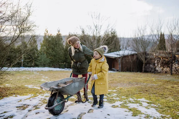 Jongen met Down syndroom werken in de tuin in de winter met zijn grootmoeder. — Stockfoto