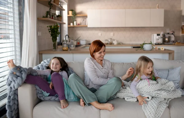 Мати з двома маленькими доньками сидить на дивані і відпочиває вдома . — стокове фото