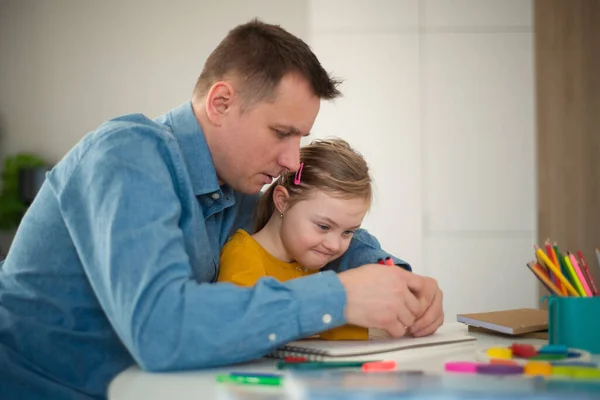 Vater mit kleiner Tochter mit Down-Syndrom lernt zu Hause. — Stockfoto