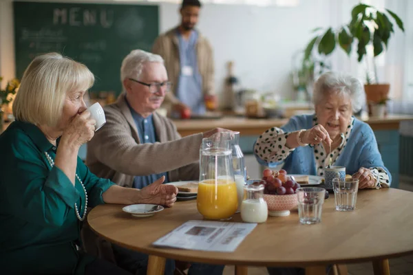 Grupo de alegres personas mayores que disfrutan del desayuno en el centro de atención a hogares de ancianos. — Foto de Stock