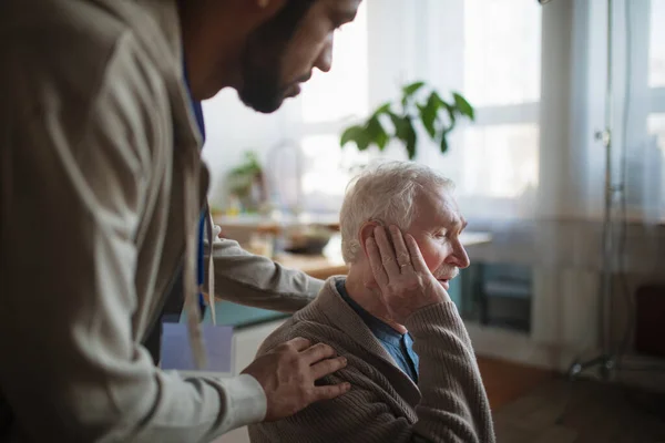 Aide à l'homme âgé pour insérer une prothèse auditive dans son oreille. — Photo