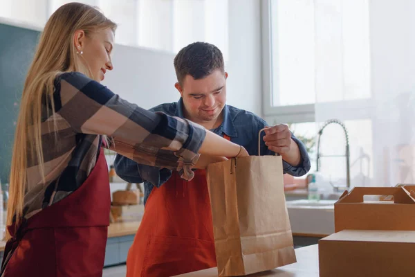 Camarero del síndrome de Down Young trabajando con un colega en un restaurante para llevar, concepto de inclusión social. — Foto de Stock