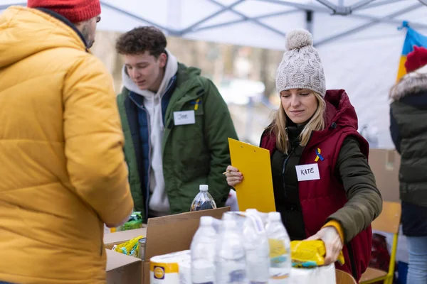 Εθελοντές που διανέμουν τρόφιμα και ποτά στους πρόσφυγες στα ουκρανικά σύνορα, έννοια ανθρωπιστικής βοήθειας. — Φωτογραφία Αρχείου