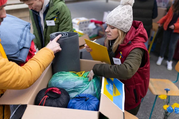 Voluntários distribuindo cobertores e outras doações para refugiados na fronteira ucraniana. — Fotografia de Stock