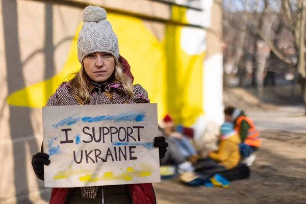 Protesta contro l'invasione russa dell'Ucraina. Donna con bandiera anti guerra vicino al campo profughi. — Foto Stock
