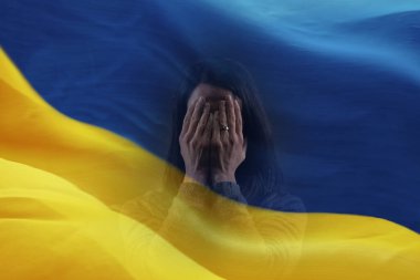 Depresyonda olan orta yaşlı bir kadının ellerini ve Ukrayna bayrağını iki kez göstermesi..