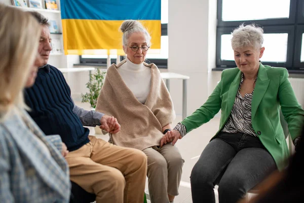 Група людей похилого віку, що тримаються за руки і моляться за Україну разом у церковному центрі.. — стокове фото