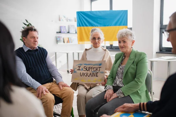 Grupp av seniorer som visar stöd när man ber för Ukraina tillsammans i kyrkan community center. — Stockfoto
