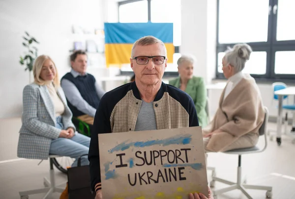 Idősek csoportja támogatást mutat, amikor együtt imádkoznak Ukrajnáért a templomi művelődési házban. — Stock Fotó
