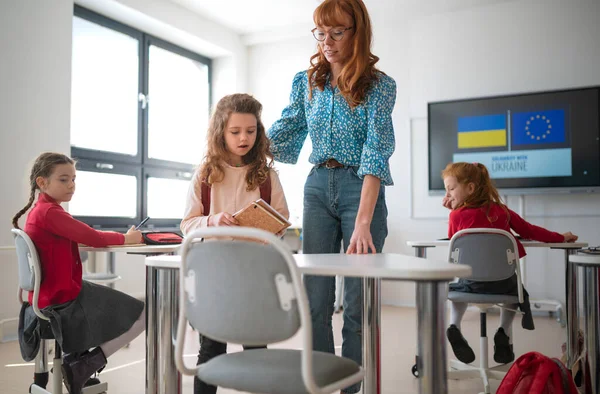 Δάσκαλος με Ουκρανή μαθήτρια στην τάξη, έννοια της εγγραφής Ουκρανικά παιδιά στα σχολεία. — Φωτογραφία Αρχείου
