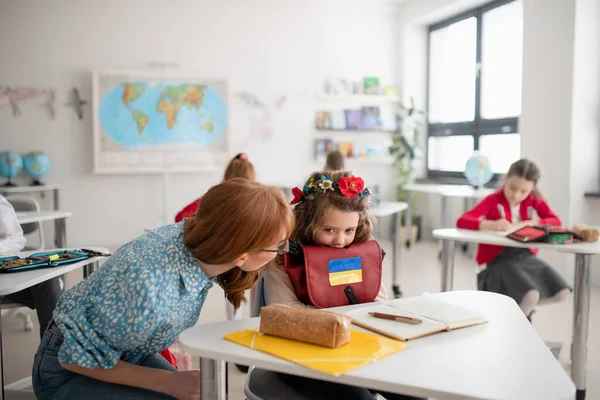 Преподаватель с украинской школьницей в классе, концепция зачисления украинских детей в школы. — стоковое фото