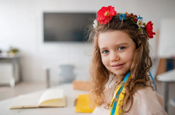 Kleines glückliches ukrainisches Mädchen blickt in die Kamera im Klassenzimmer, Konzept der Einschulung ukrainischer Kinder in Schulen. — Stockfoto