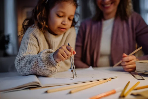 Mère aidant sa fille à faire ses devoirs, dessinant un cercle avec des compas le soir à la maison. — Photo