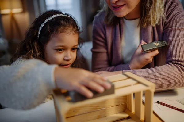 Felice bambina ristrutturare una cassa di legno insieme a sua madre a casa. — Foto Stock