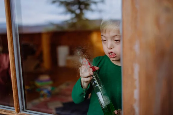Junge mit Down-Syndrom putzt Fenster zu Hause. — Stockfoto