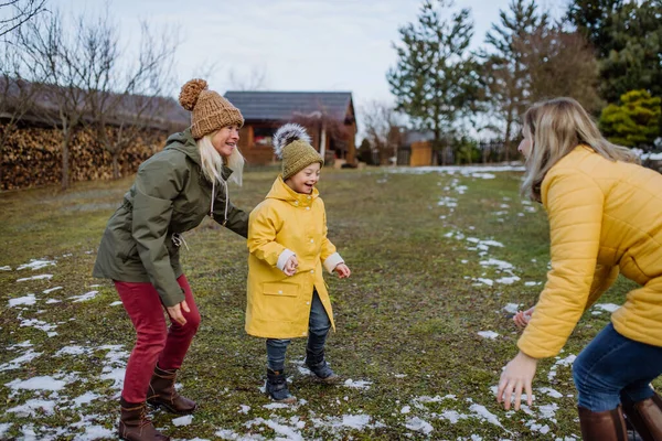 Jongen met Down syndroom met zijn moeder en grootmoeder spelen in de tuin in de winter. — Stockfoto