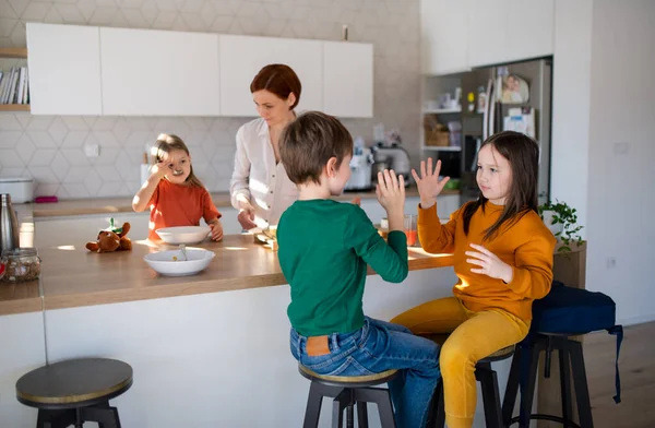 三个小孩的母亲在家里厨房准备早餐. — 图库照片