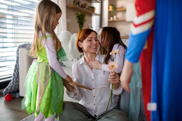 Mother of little children in costumes getting present from them at home. — Stock Photo, Image