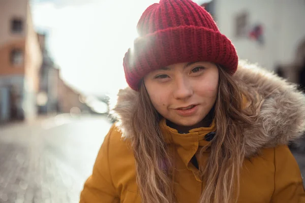 Jovem feliz com síndrome de Down weraing parka e chapéu, andando na cidade e olhando para a câmera. — Fotografia de Stock