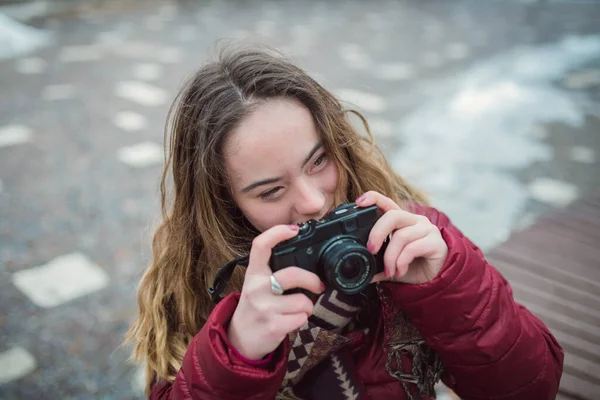 Jonge vrouw met Down syndroom met behulp van camera in de stad in de winter en op zoek naar camera. — Stockfoto
