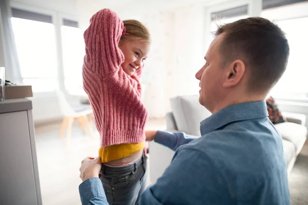 Otec pomáhá své malé dceři s Downovým syndromem nosit doma kalhoty. — Stock fotografie