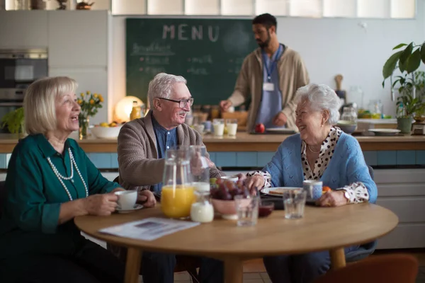 Grupo de alegres personas mayores que disfrutan del desayuno en el centro de atención a hogares de ancianos. — Foto de Stock