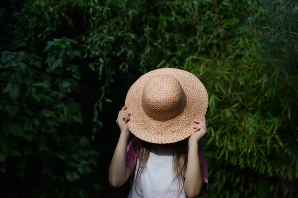 Oigenkännlig liten flicka i hatt står utomhus på gården. — Stockfoto