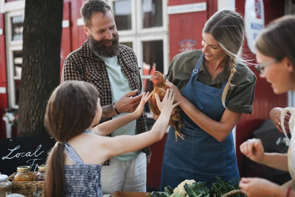 Felice bambina accarezzando gallina all'aperto al mercato agricolo familiare locale. — Foto Stock