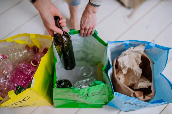 Frau wirft leere Glasflasche in Recyclingbehälter in Küche. — Stockfoto