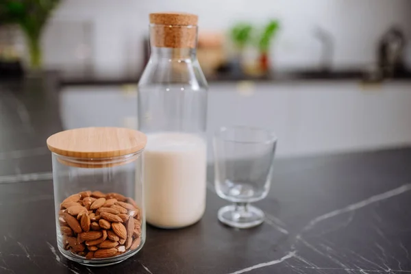 Leite de amêndoa e vidro no balcão da cozinha. Conceito de produto vegan saudável. — Fotografia de Stock