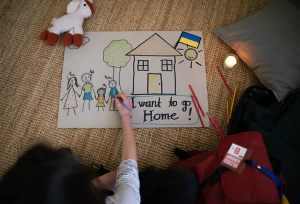 Bovenaanzicht van de Oekraïense vluchteling schoolmeisje vermist huis en het tekenen van haar familie. Oekraïense oorlogsconcept. — Stockfoto