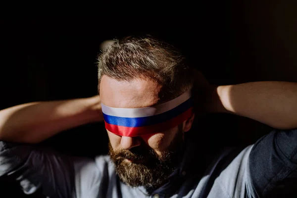 Uomo con bandiera russa benda su sfondo nero, propaganda russa chiuso popoli occhi concetto. — Foto Stock